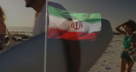 Iranian flag waving at beach with carefree surfers