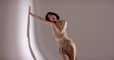 Contemplative Female Pose Against Minimalist Taupe Background