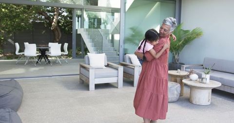 Grandmother Hugging Granddaughter in Modern Living Space Outdoors
