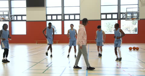 Coach Directs Basketball Team Warm-Up in School Gym
