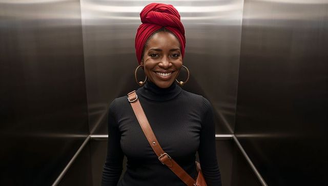 Stylish woman with red headwrap in modern elevator