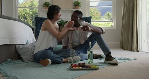 Romantic Couple Enjoying Wine and Fruit Picnic Indoors