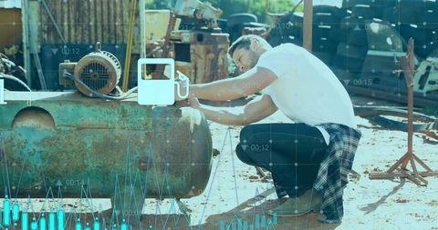 Kneeling mechanic turning valve on rusted industrial tank in scrapyard with data overlays