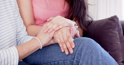 Mother and Daughter Holding Hands with Love on Sofa