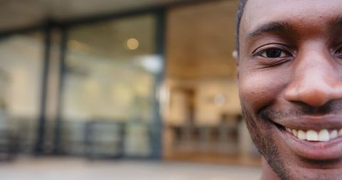 Half-face of smiling man in front of modern café setting with glass windows