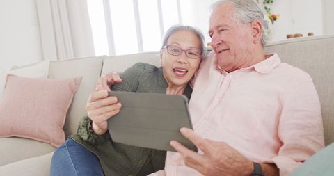 Happy Elderly Couple Enjoying Tablet Together on Cozy Couch - Download Free Stock Images Pikwizard.com