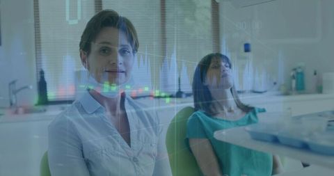 Female dentist consulting patient in modern dental clinic with digital chart overlay