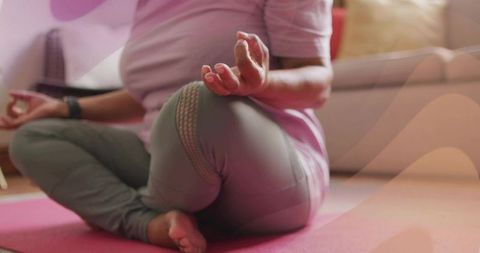 Senior indian woman practicing seated meditation on pink yoga mat in home living room