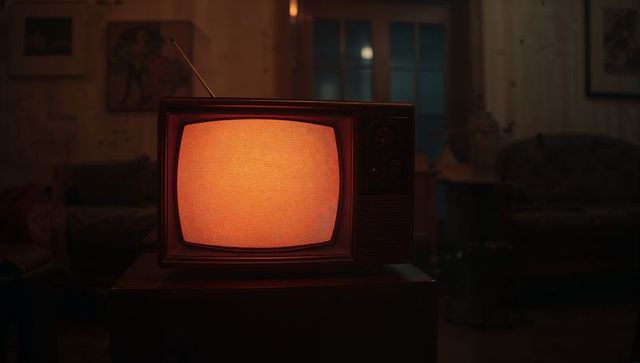 Retro tv glowing with static light in cozy vintage living room