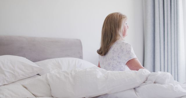 Senior Woman Sitting on Bed Looking Out Window in Morning Light - Download Free Stock Images Pikwizard.com