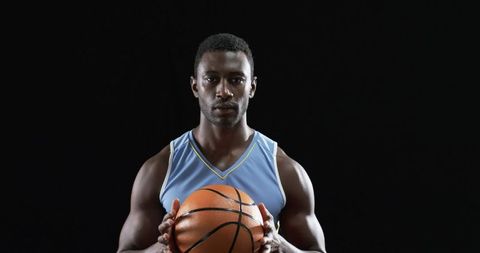 Confident Basketball Player Holding Ball Against Black Background