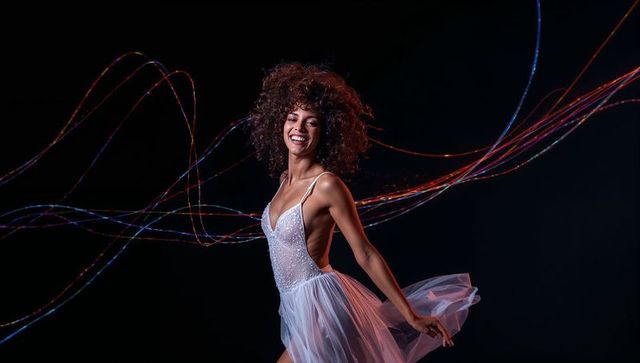 Twirling dancer wearing beaded bodice and flowing tulle skirt, colorful light trails