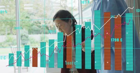 Carer helping senior at home with digital health and financial analytics overlaying glass