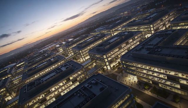 Twilight corporate campus glowing with illuminated glass office blocks and rooftop units