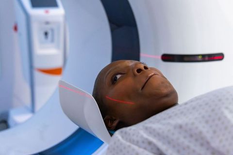 African woman undergoing ct scan with red laser alignment on head in hospital radiology