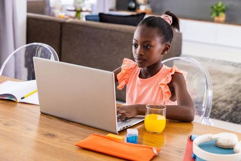 Focused african american girl studying on laptop at home, remote learning and homework