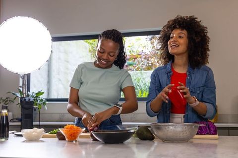 African American women cooking together in modern kitchen filming vibrant plant-based meal