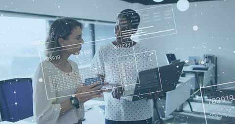 Two Women Collaborating Over Laptop and Mobile with Holographic Data Dashboards in Office