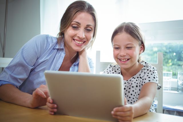 Smiling mother and daughter using digital tablet - Download Free Stock Photos Pikwizard.com