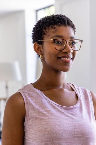 Confident african woman smiling in soft light wearing glasses and pink top