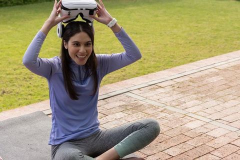 Young asian woman putting on vr headset during outdoor yoga on patio
