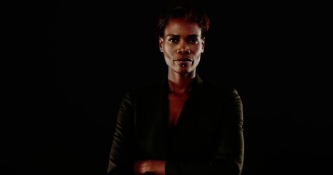 Confident Businesswoman Standing with Poise Against Dark Background