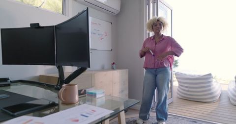 Leading remote presentation from bright home office doorway, woman holding marker