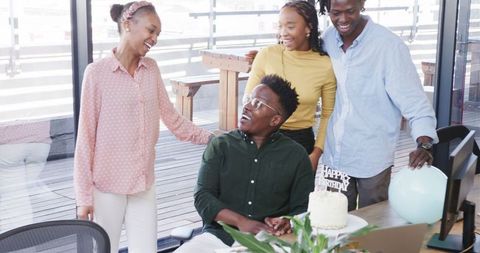 Office birthday celebration with joyful colleagues and cake