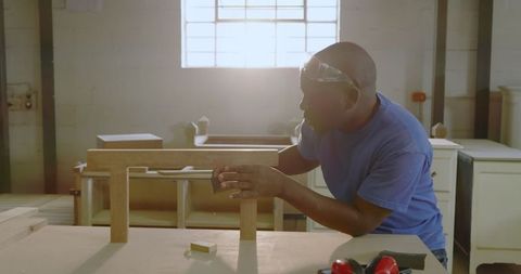 Artisan Skillfully Constructs Wooden Beam Support in Workshop