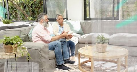 Mature couple monitoring blood pressure at home using digital arm cuff on cozy sofa