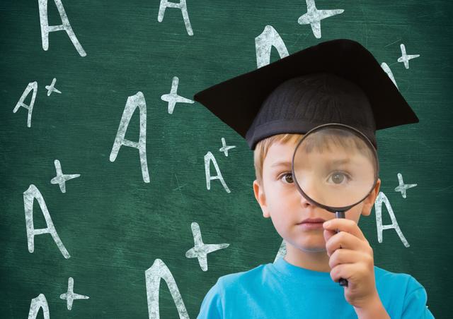 Young boy wearing graduation cap holding magnifying glass in front of chalkboard with A+ symbols. Ideal for educational materials, school promotions, academic success stories, and children's learning resources.