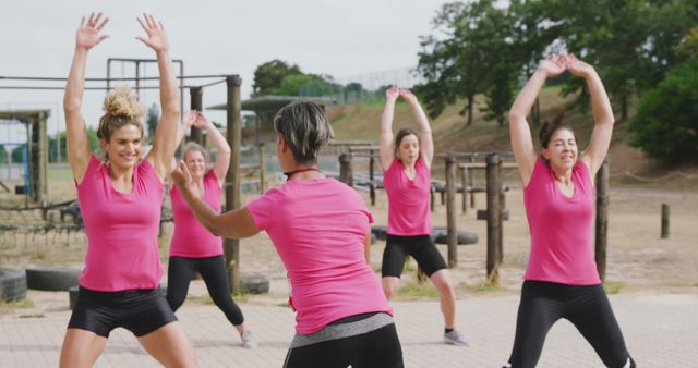 Caucasian female fitness trainer motivating group of happy female friends cross training at bootcamp. Female fitness, challenge and healthy lifestyle.