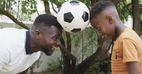 Playful Father and Son Bonding with Soccer Ball Outdoors
