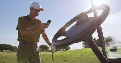 Golfer Using Smartphone on Sunny Golf Course Break