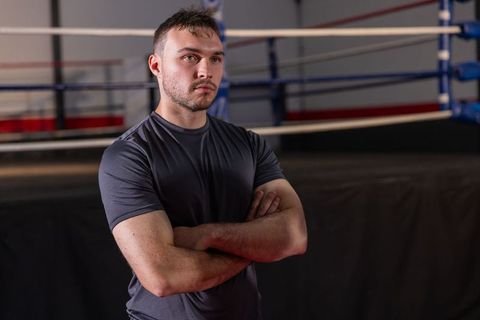 Determined boxer standing with arms crossed beside ring showing focus and strength