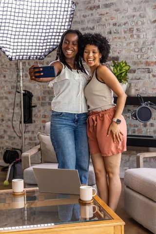 Two african american content creators taking selfie in home studio with streaming gear