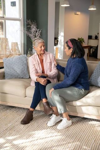 Senior and middle-aged women sharing supportive conversation on cozy living room sofa