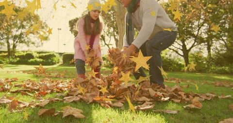 Father and daughter raking autumn leaves in sunny park with gold star sparkle overlay