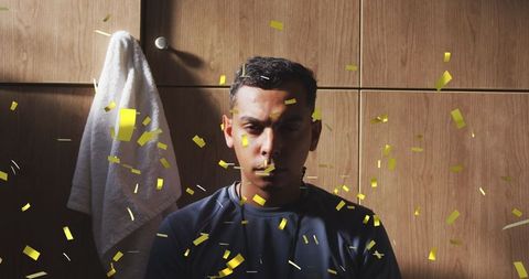 Somber Football Player with Confetti in Changing Room