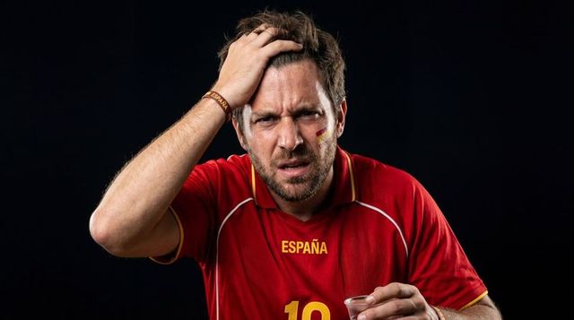 Frustrated spain soccer fan wearing españa jersey and wristband holding cup closeup