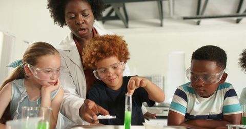 Diverse teacher guiding children in hands-on school science experiment with safety goggles