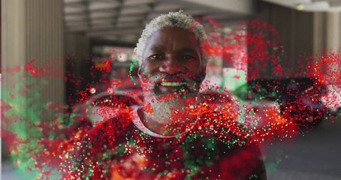 Senior man smiling wearing red sweater in parking garage with red green particle burst