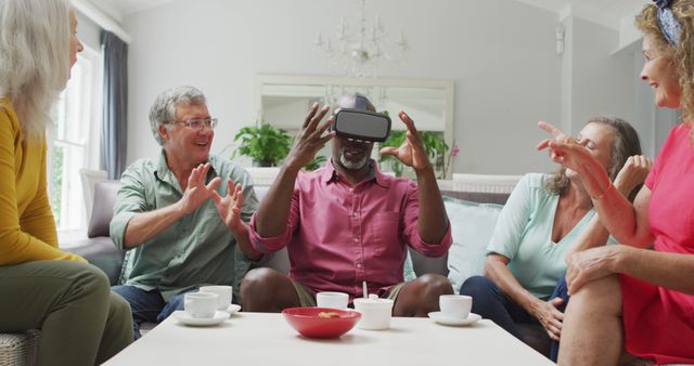 Image of diverse female and male senior friends using vr headset and having fun. retirement lifestyle, spending quality time with friends and technology.