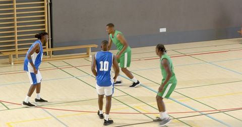 Four basketball players executing fake drive, pass and jump shot in fast indoor game