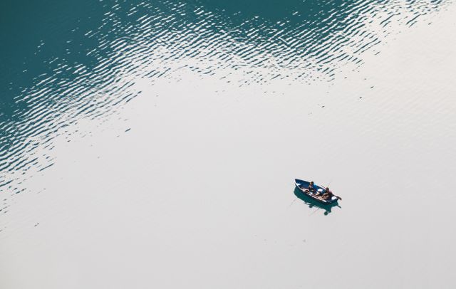 Boat floats alone on a clear, tranquil lake creating a serene and peaceful picture. Ideal for concepts related to solitude, nature, outdoor adventures, and calmness. Perfect for travel brochures, relaxation themes, and minimalistic designs needing a sense of peace and escape.