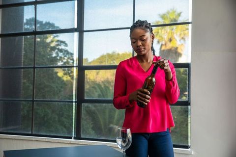 Elegant woman celebrating with wine at rustic windowed interior