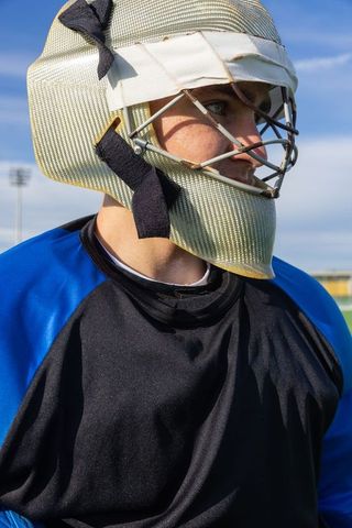Field hockey goalkeeper with protective gear under blue sky