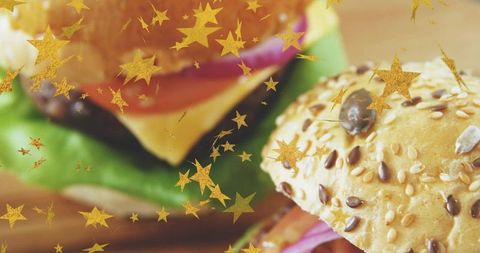 Seeded gourmet burger close-up showing melted cheese, lettuce and golden star confetti