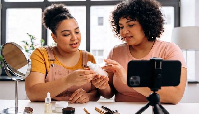 Two creators testing skincare while filming beauty tutorial with tripod and makeup tools