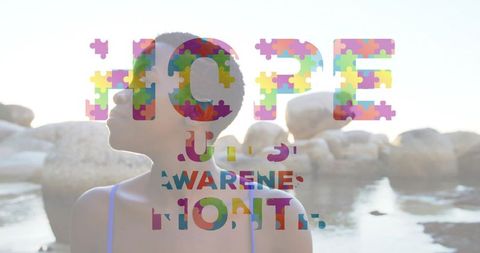 Backlit woman at coastal cove with colorful puzzle typography overlay promoting awareness